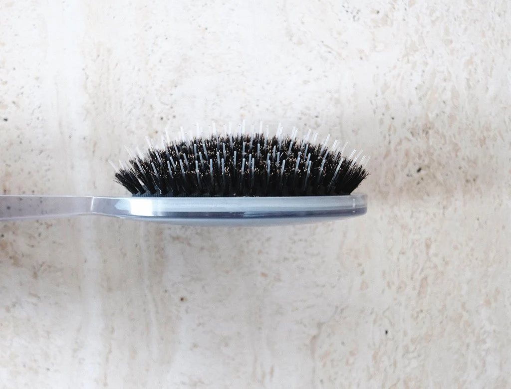 Hairbrush with black bristles on a textured white background