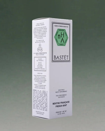 A tall white rectangular box of Bastét Nana Hydrogenated Toothpaste, French Mint flavor, shown on a dark green gradient background.