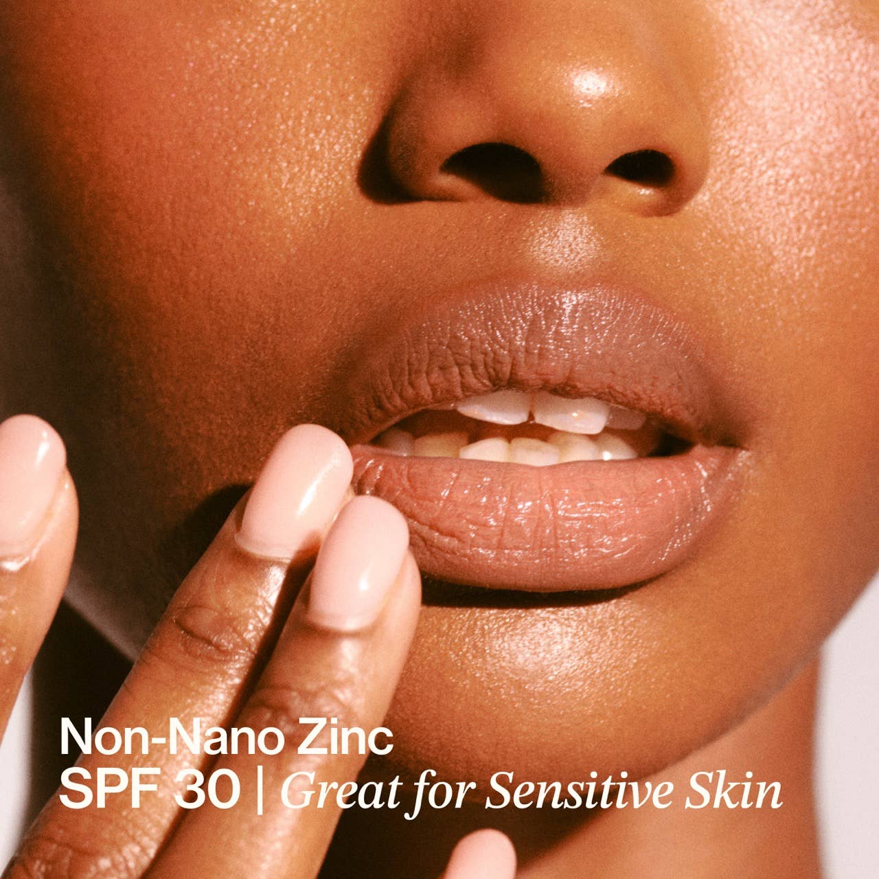 Close-up of a person's lips with a hand applying a product, text about Non-Nano Zinc SPF 30 and sensitive skin.